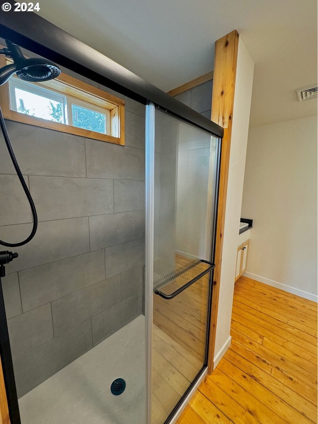 bathroom with hardwood / wood-style flooring and an enclosed shower