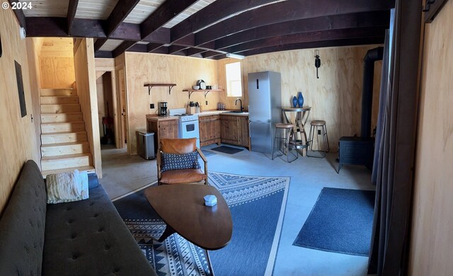 interior space featuring a wood stove, sink, and wooden walls