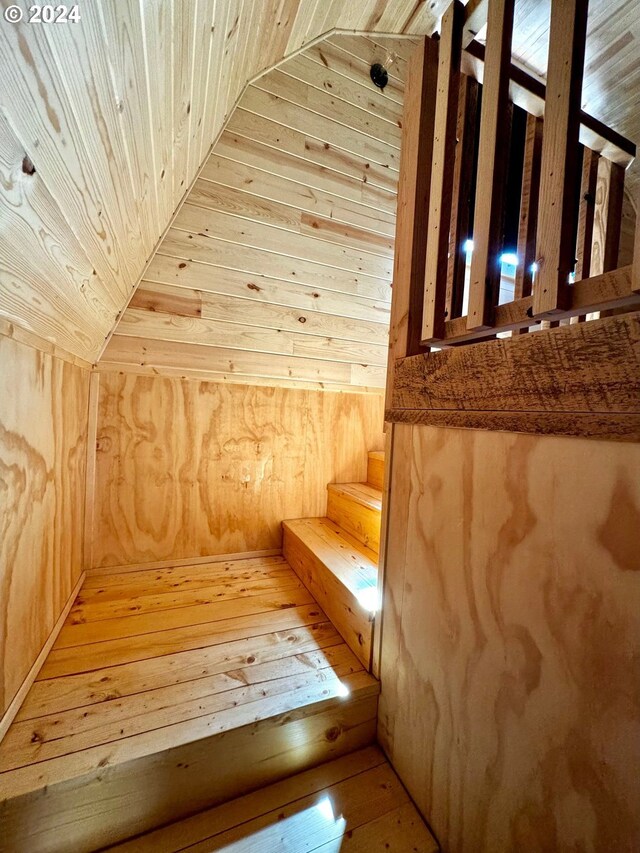 stairway with wood walls, wooden ceiling, and hardwood / wood-style floors