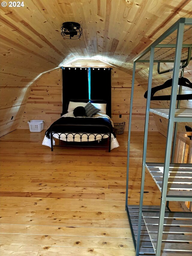 bedroom with lofted ceiling, hardwood / wood-style floors, wooden walls, and wooden ceiling