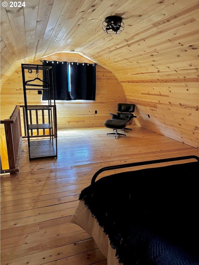 unfurnished bedroom with wood walls, wooden ceiling, vaulted ceiling, and light wood-type flooring