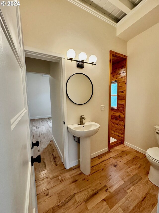 bathroom featuring toilet, wood walls, ornamental molding, and hardwood / wood-style floors