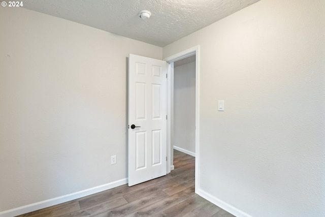 spare room with light hardwood / wood-style floors and a textured ceiling