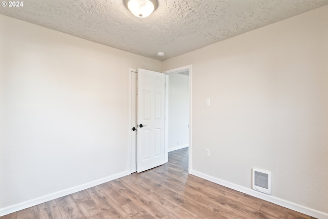 spare room with hardwood / wood-style floors and a textured ceiling