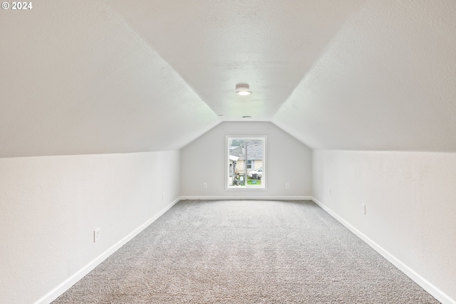 bonus room featuring a textured ceiling, carpet floors, and lofted ceiling