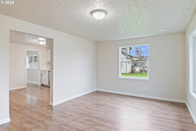 unfurnished room featuring a textured ceiling, light wood-type flooring, and plenty of natural light