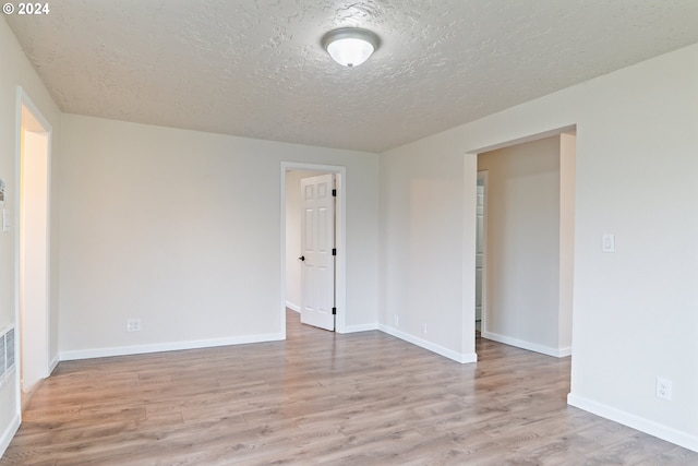 spare room with light hardwood / wood-style flooring and a textured ceiling