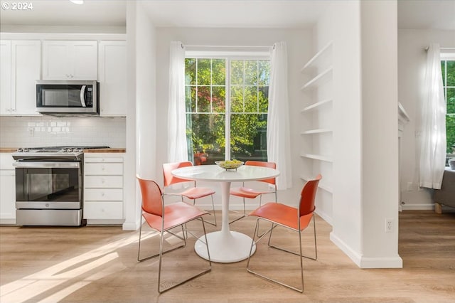 kitchen featuring white cabinets, stainless steel appliances, light wood-type flooring, and tasteful backsplash