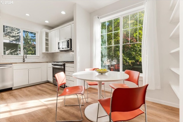 kitchen with appliances with stainless steel finishes, tasteful backsplash, sink, and white cabinets