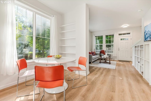 dining area featuring light wood-type flooring and built in shelves