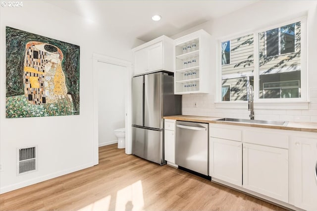 kitchen featuring white cabinets, sink, tasteful backsplash, appliances with stainless steel finishes, and light hardwood / wood-style floors