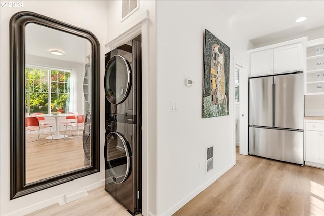 clothes washing area with light hardwood / wood-style floors and stacked washing maching and dryer