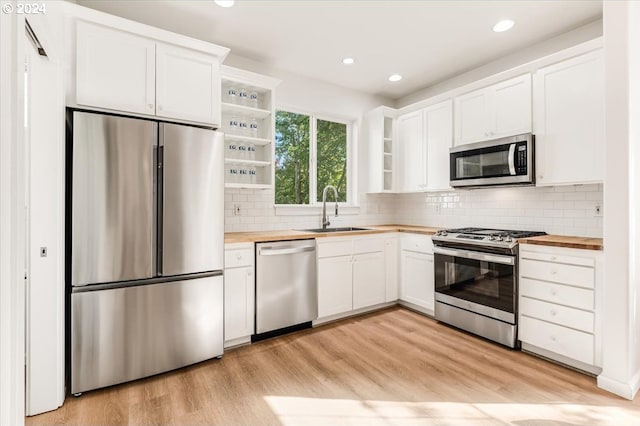 kitchen featuring light wood-type flooring, sink, white cabinetry, butcher block counters, and appliances with stainless steel finishes