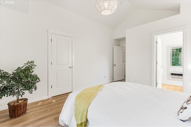 bedroom with vaulted ceiling, hardwood / wood-style floors, and ensuite bathroom