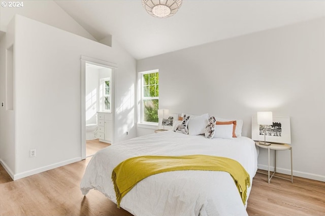 bedroom with light wood-type flooring, connected bathroom, and vaulted ceiling