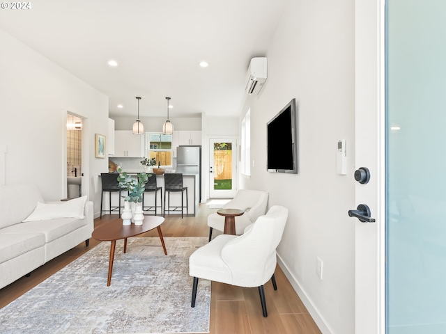 living room with a wall mounted air conditioner and light hardwood / wood-style floors