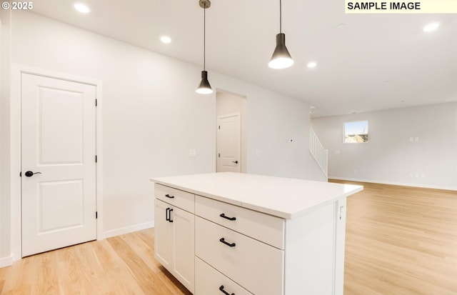 kitchen featuring a kitchen island, light hardwood / wood-style floors, hanging light fixtures, and white cabinets