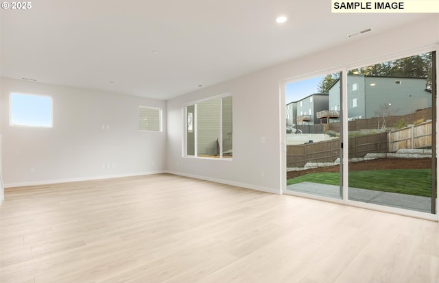 spare room featuring a wealth of natural light and light hardwood / wood-style flooring