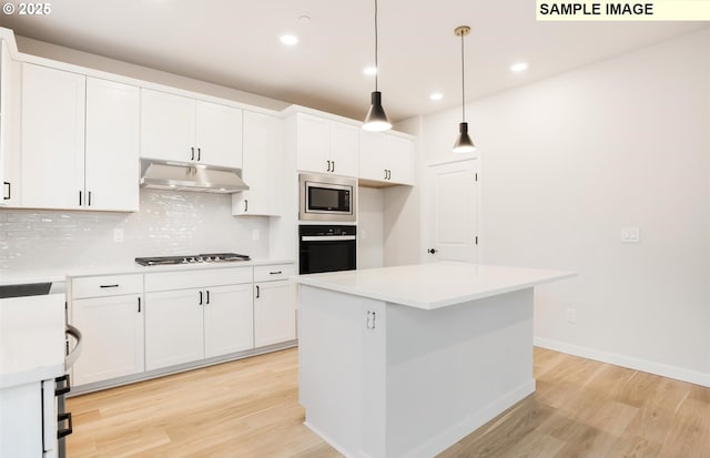 kitchen with white cabinetry, a center island, hanging light fixtures, appliances with stainless steel finishes, and decorative backsplash