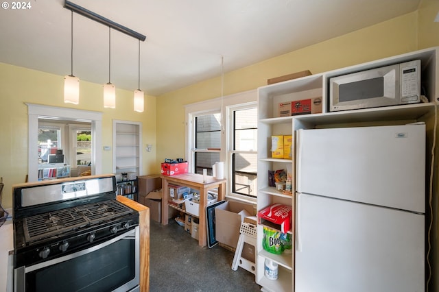 kitchen with plenty of natural light, decorative light fixtures, white appliances, and dark carpet