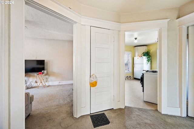 hall featuring a textured ceiling and light carpet