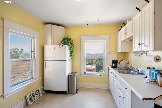 kitchen with white refrigerator, white cabinetry, and plenty of natural light