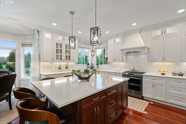 kitchen with a kitchen breakfast bar, dark hardwood / wood-style flooring, premium range hood, double oven range, and a kitchen island