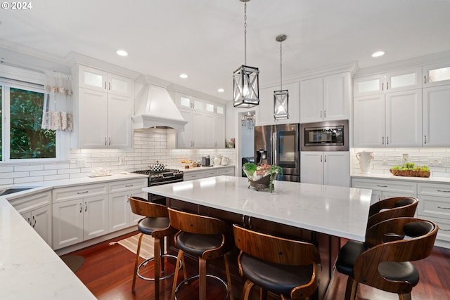 kitchen with custom exhaust hood, a breakfast bar, white cabinets, light stone countertops, and stainless steel appliances