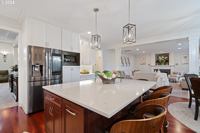 kitchen with stainless steel fridge, black microwave, dark wood-type flooring, decorative light fixtures, and white cabinets