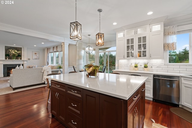 kitchen with dark hardwood / wood-style flooring, crown molding, dishwasher, a center island, and hanging light fixtures