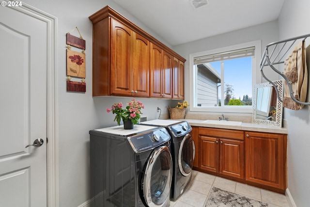 clothes washing area with sink, light tile patterned floors, cabinets, and independent washer and dryer