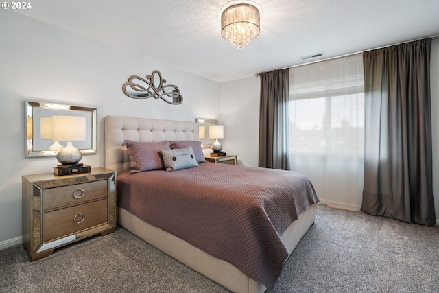 carpeted bedroom featuring a textured ceiling and an inviting chandelier