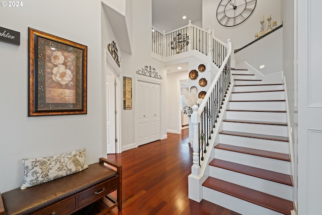 entryway with a towering ceiling and dark wood-type flooring