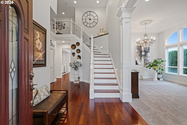 entrance foyer with decorative columns, dark wood-type flooring, and a chandelier