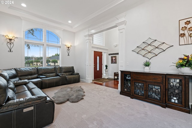 living room with wood-type flooring, ornamental molding, a high ceiling, and ornate columns