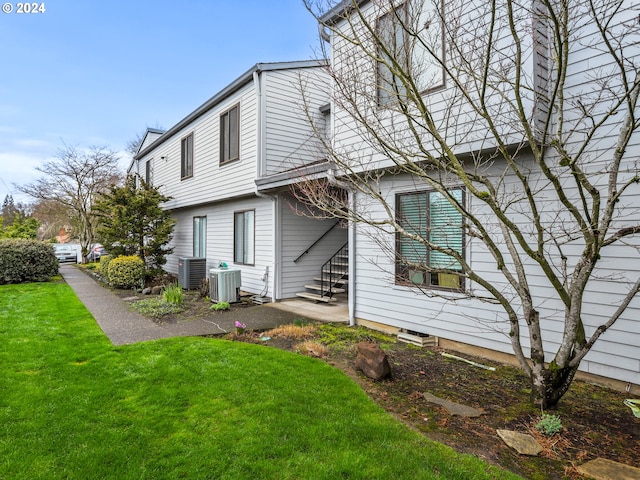 exterior space featuring central air condition unit and a lawn