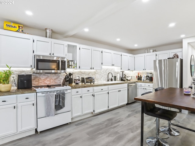 kitchen featuring backsplash, light hardwood / wood-style floors, stainless steel appliances, and white cabinetry