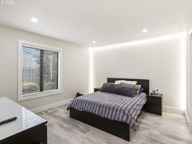 bedroom featuring light hardwood / wood-style floors and a textured ceiling