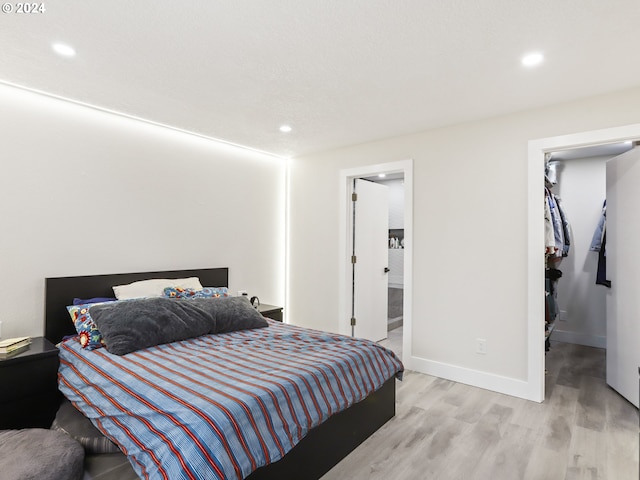 bedroom with connected bathroom and light wood-type flooring