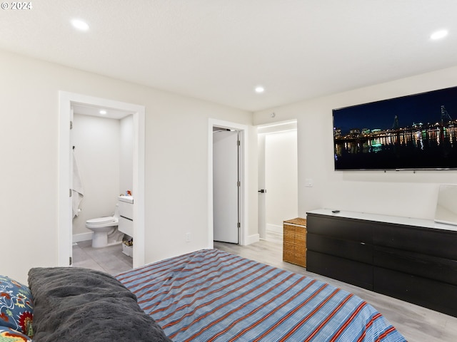 bedroom featuring connected bathroom and light wood-type flooring