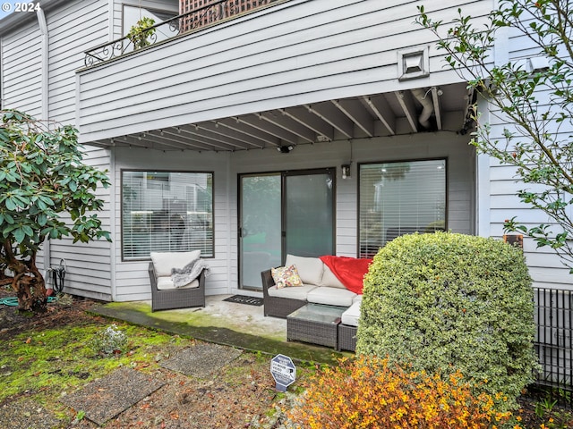 view of exterior entry with outdoor lounge area, a patio, and a balcony