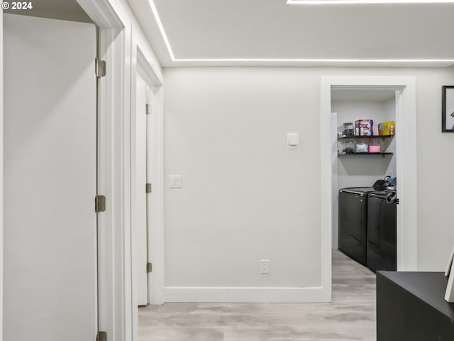 hall with washing machine and clothes dryer and light wood-type flooring