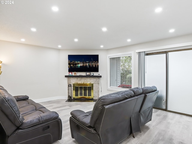 living room featuring a stone fireplace and light hardwood / wood-style flooring