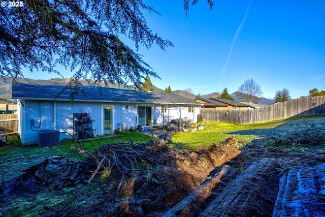 back of property featuring central AC unit and a lawn