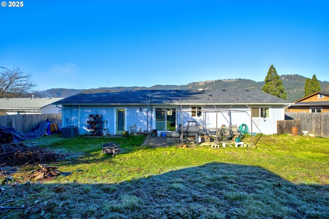 back of property with a mountain view, a yard, and an outdoor fire pit