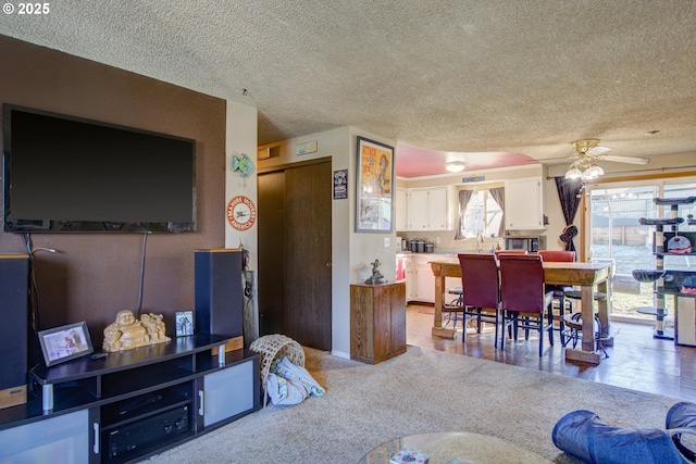 living room with ceiling fan, light colored carpet, sink, and a textured ceiling