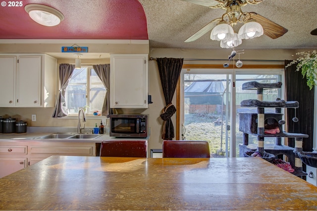 kitchen featuring white cabinetry, ceiling fan, sink, and a textured ceiling