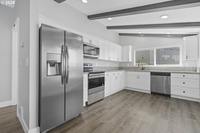 kitchen with appliances with stainless steel finishes, lofted ceiling with beams, light stone counters, white cabinets, and dark hardwood / wood-style floors