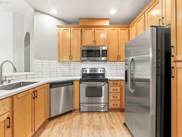 kitchen with decorative backsplash, sink, appliances with stainless steel finishes, and light hardwood / wood-style flooring