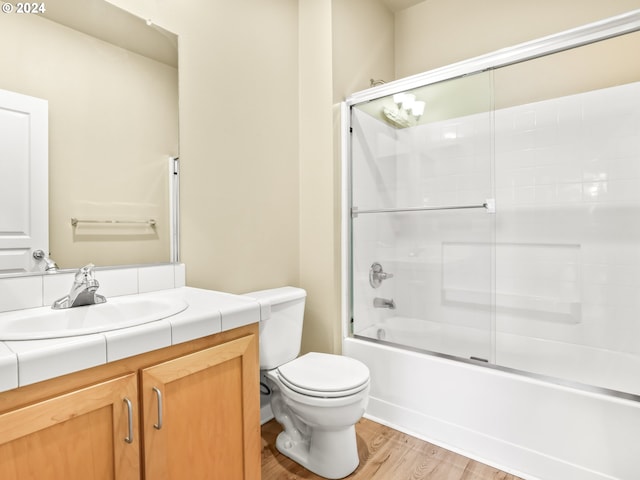 full bathroom with toilet, vanity, wood-type flooring, and combined bath / shower with glass door